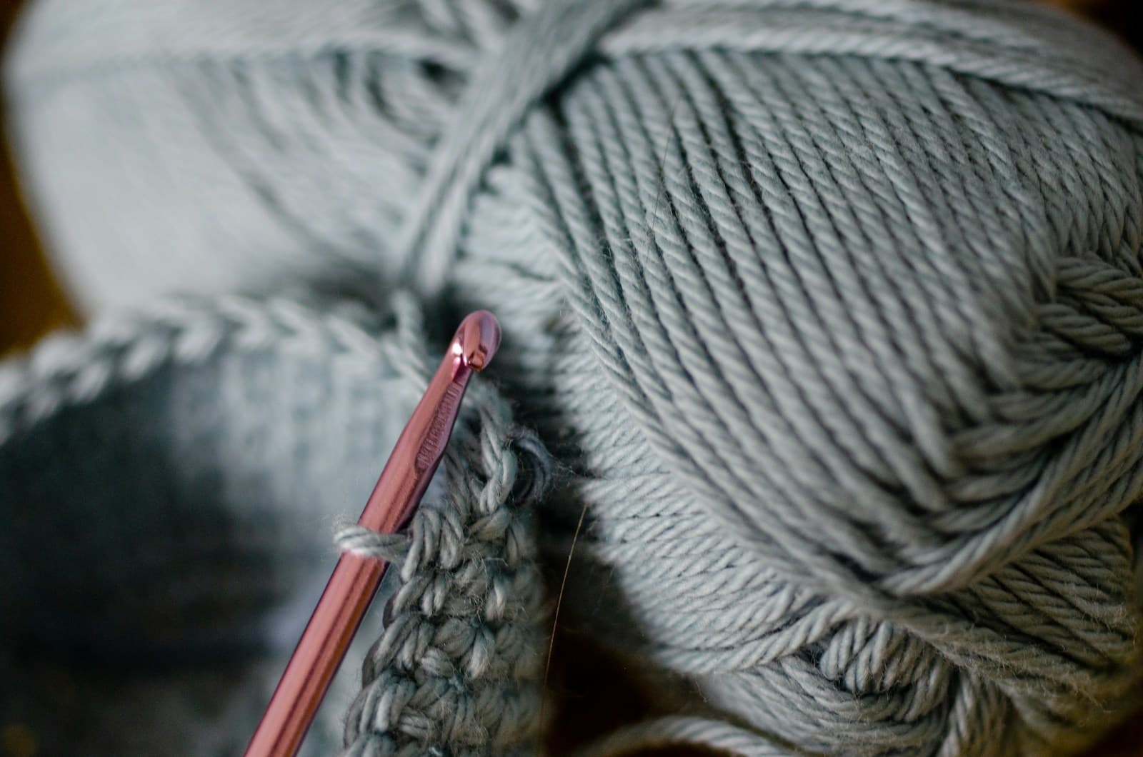 A ball of yarn beside a crochet hook on a table