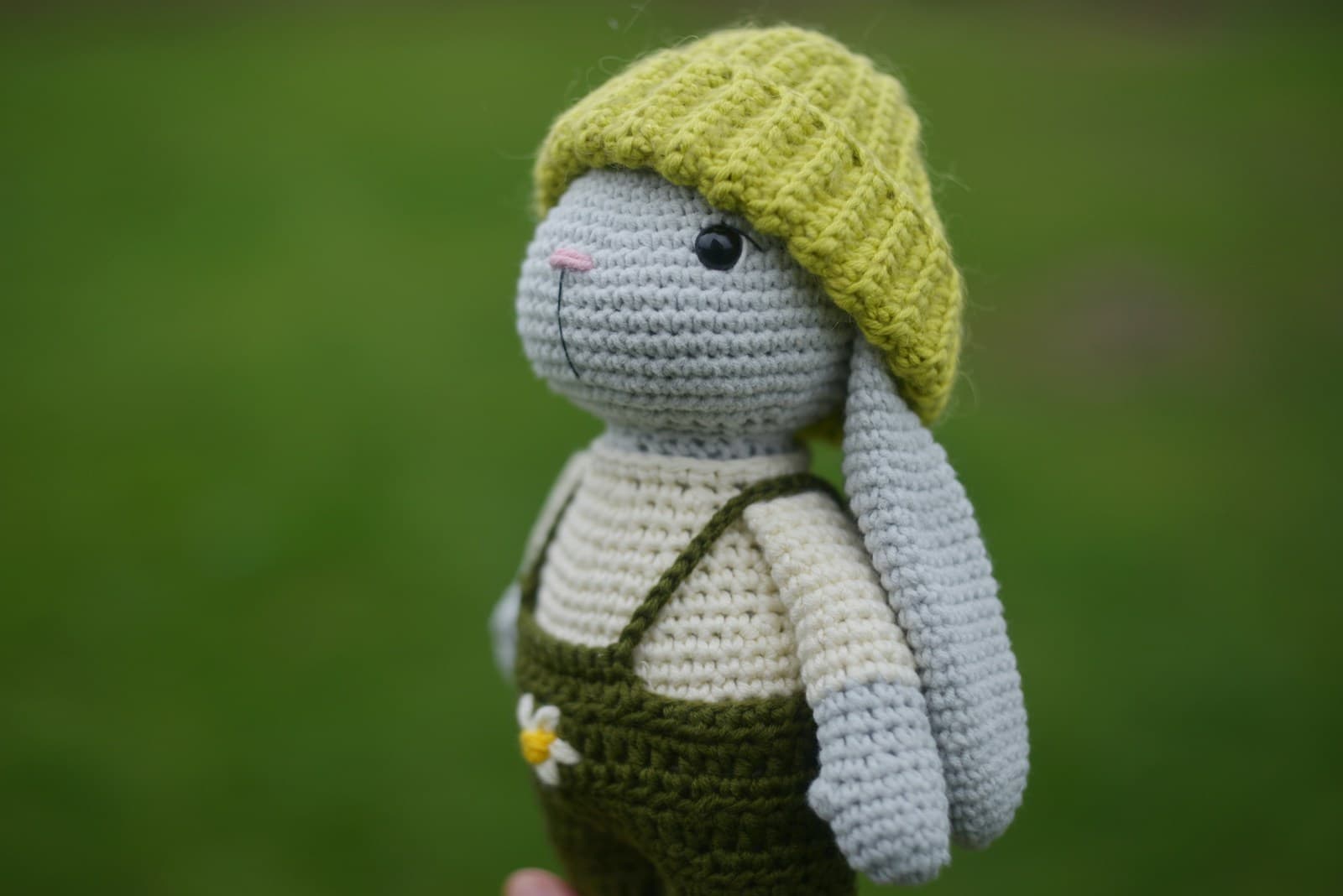 A crocheted amigurumi bunny wearing a hat and overalls