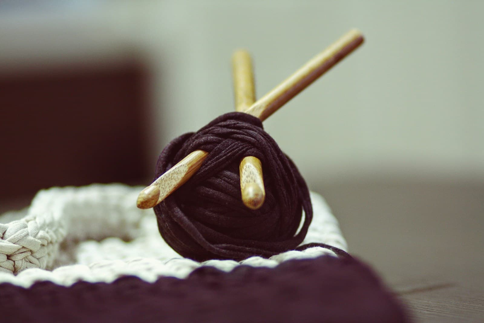 Two wooden crochet hooks resting on a skein of brown yarn