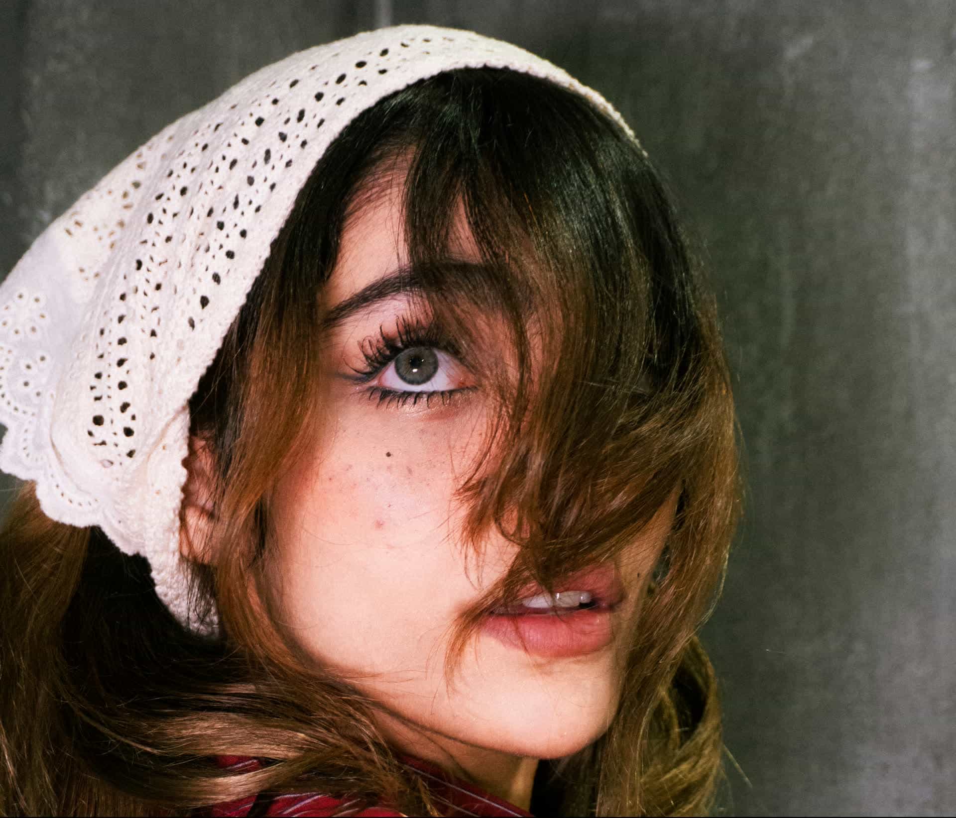 A woman wearing a printed fabric bandana tied over her hair, retro pin-up style, with sunglasses