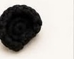 Small flattened black crocheted panda ear, made by working single crochet in a spiral and leaving the piece unstuffed