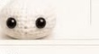 Finished white crocheted panda head with two round safety eyes attached, ready for the ears and eye patches