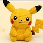 Finished crocheted amigurumi Pikachu sitting upright, holding its lightning-bolt tail in one hand
