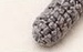Small lightly stuffed grey crocheted raccoon arm, a short tapered cylinder